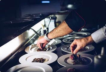 Chef die zorgvuldig meerdere gerechten presenteert in een professionele restaurantkeuken.