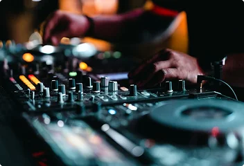 Close-up van een DJ die muziek mixt op professionele apparatuur tijdens een avond evenement.
