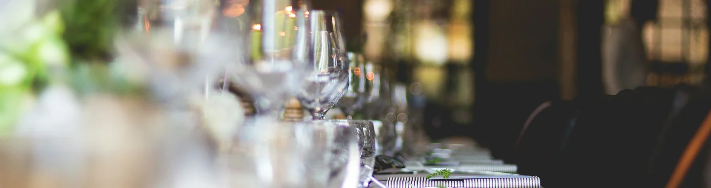 Elegante restauranttafel gedekt met glaswerk en servies in een zacht verlichte, verfijnde eetomgeving.