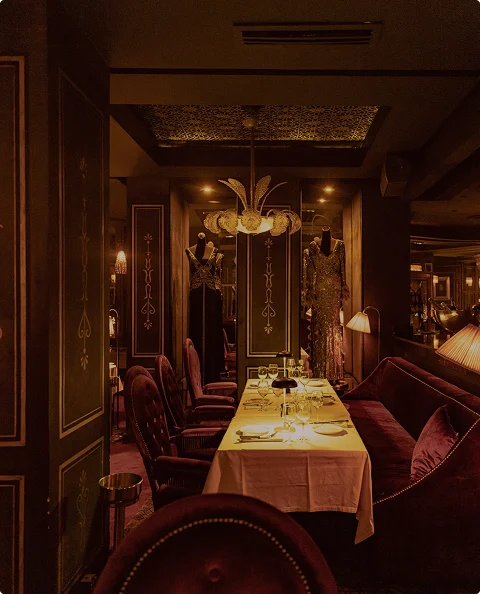 Elegante eetzaal van het restaurant met warme verlichting, fluwelen zitplaatsen en een prachtig gedekte lange tafel.