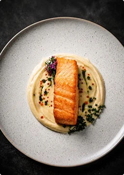 In de pan gebakken zalmfilet geserveerd op een romige puree met kruiden en een delicate garnering.