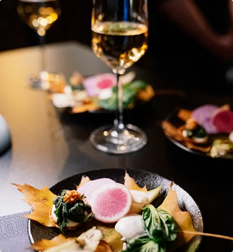 Elegante seizoensgebonden gerechten geserveerd met een glas witte wijn in een warme restaurantomgeving.